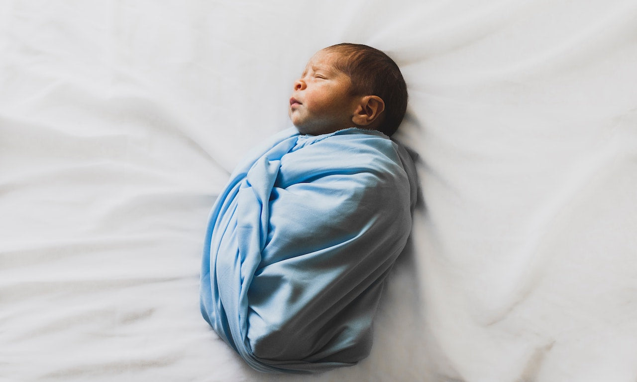 baby sleeping in blue swaddle